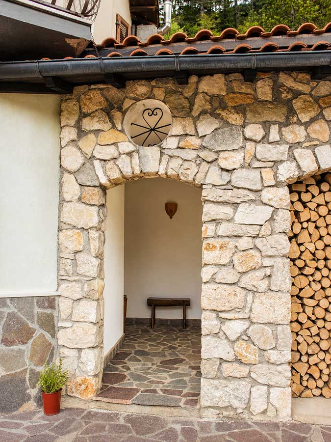 Appartamento Opi La Sosta con ingresso esterno in pietra, portico coperto e dettagli autentici di montagna.