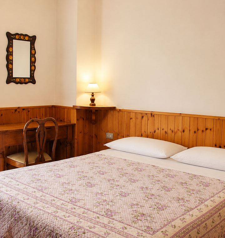 Camere Opi al B&B La Sosta, camera matrimoniale con scrivania, arredi in legno e ambiente luminoso.