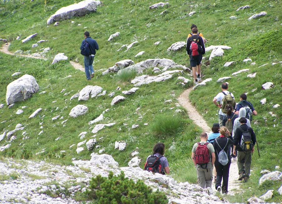 Cosa fare a Opi, escursionisti sui sentieri del Parco Nazionale d’Abruzzo tra prati, rocce e natura di montagna.